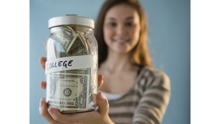 Hispanic girl holding â'college' savings jar