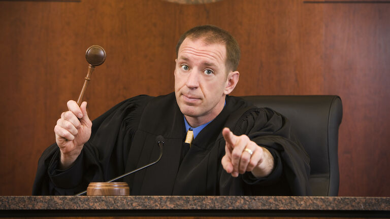 Upset judge swinging gavel and pointing