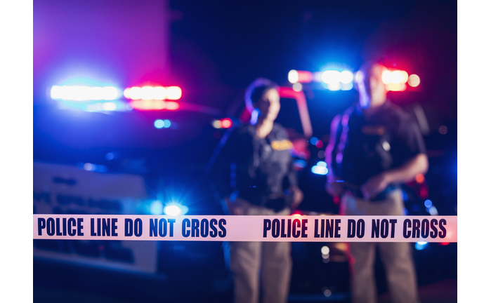 Two police officers standing in front of patrol cars