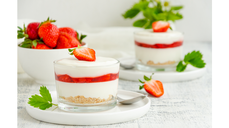 No baked strawberry cheesecake in a glass on a wooden background. Summer cold dessert. Horizontal, copy space.