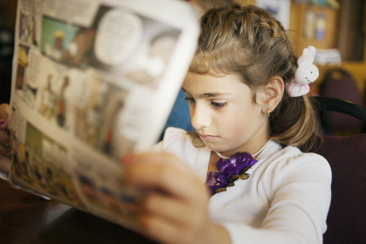 Mixed race girl reading newspaper