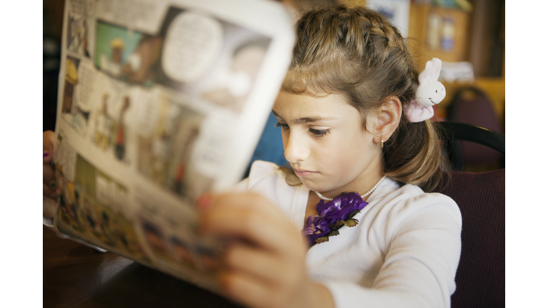 Mixed race girl reading newspaper
