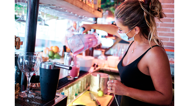 waitress with face mask preparing a cocktail at the restaurant - coronavirus and small business concept