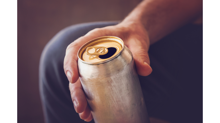 Man drinking a cold beer after work in the evening. Hand holding a aluminum can.