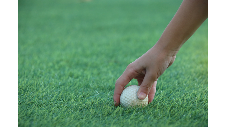 Hand of caddie holding golf ball on green outdoor sport challenge the competitive