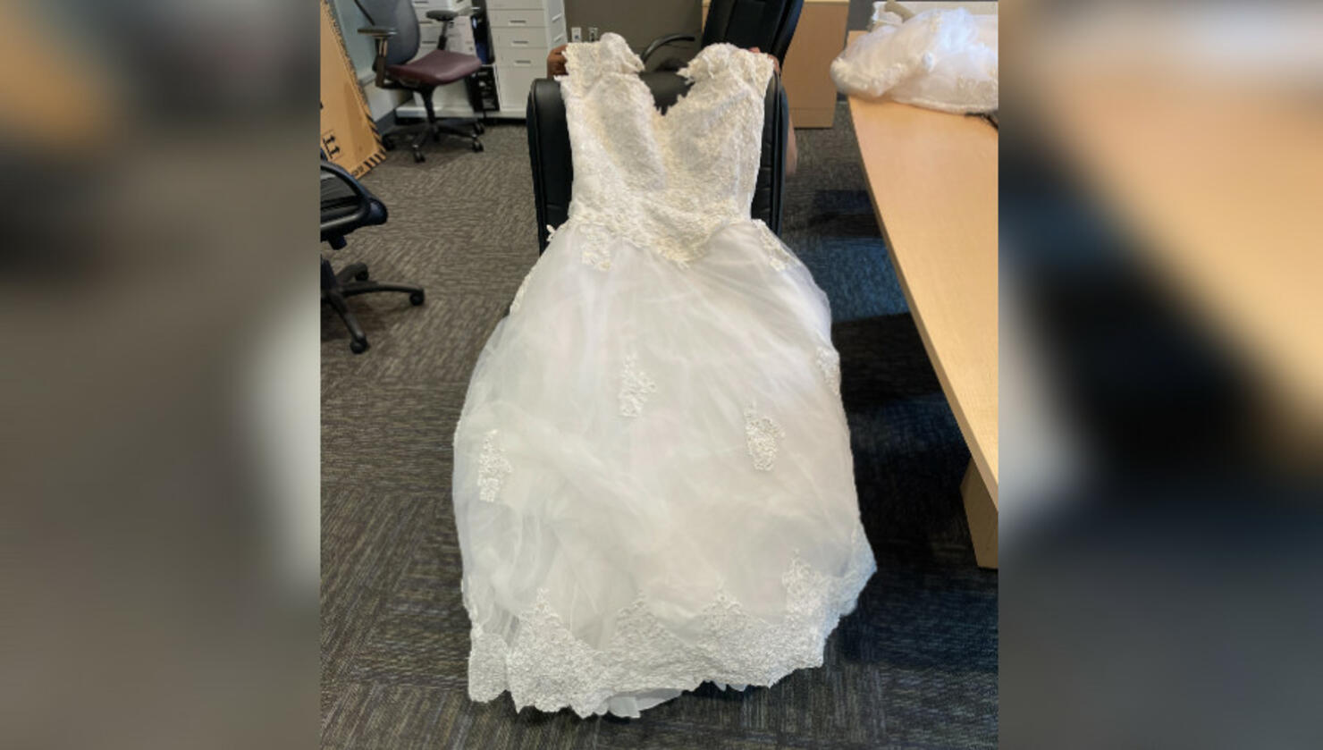 A wedding dress on a desk chair. 