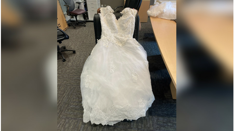 A wedding dress on a desk chair. 