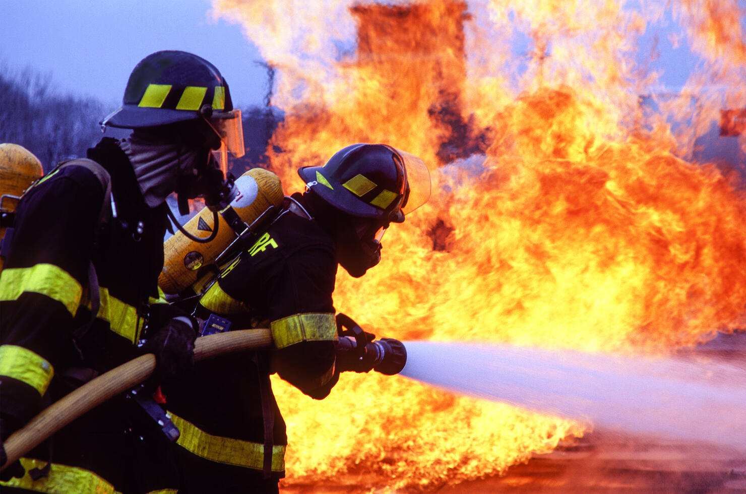 Firemen fighting blaze with hose.