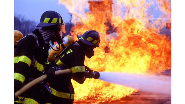 Firemen fighting blaze with hose.