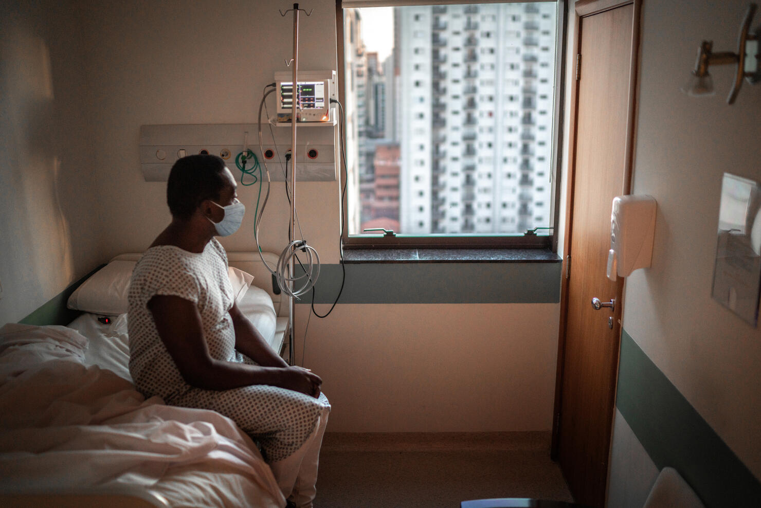 Senior patient using mask looking through window at hospital