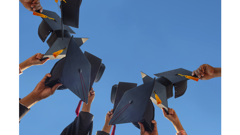 Low Angle View Of People Holding Cap Against Clear Sky