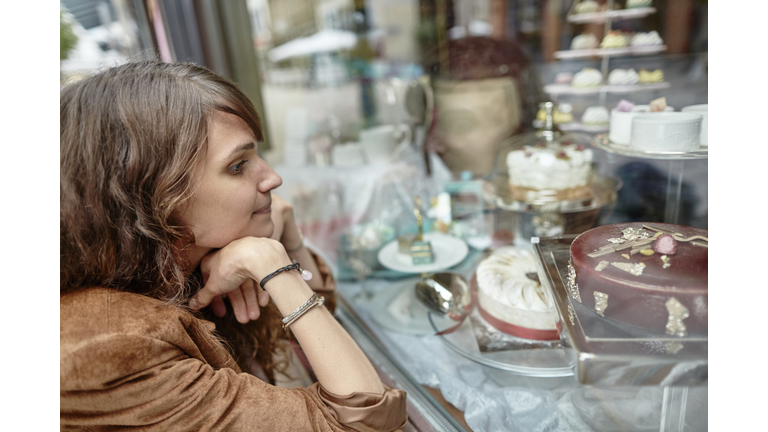 Young woman looking in shop window of a confectioner