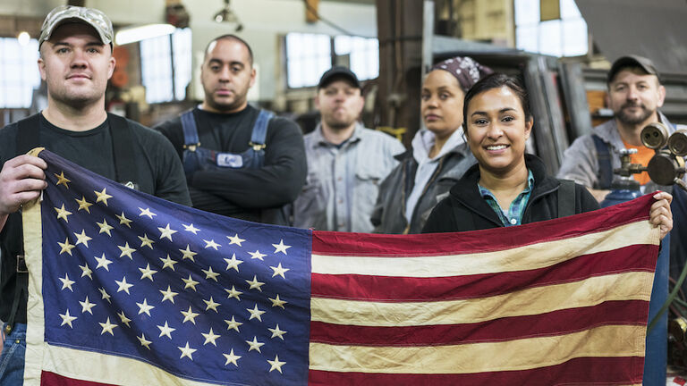 Workers holding American flag in factory