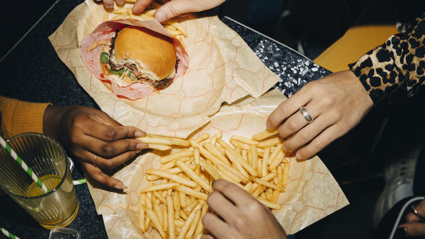 High angle view of friends eating burger and french fries at table in cafe