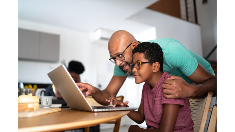 Father encouraging son on homeschooling or doing a video call/watching a movie