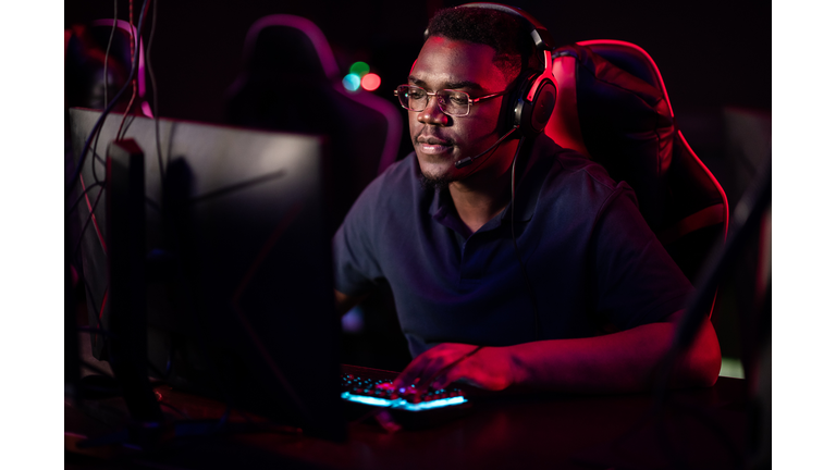 An african guy wearing headphones and glasses leads an online stream during the computer games championship