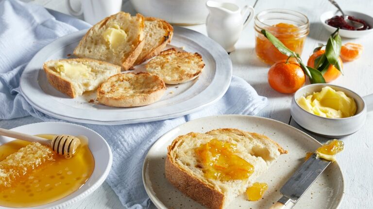 Plates of toast with butter and marmalade, dishes of honey, butter and jams.