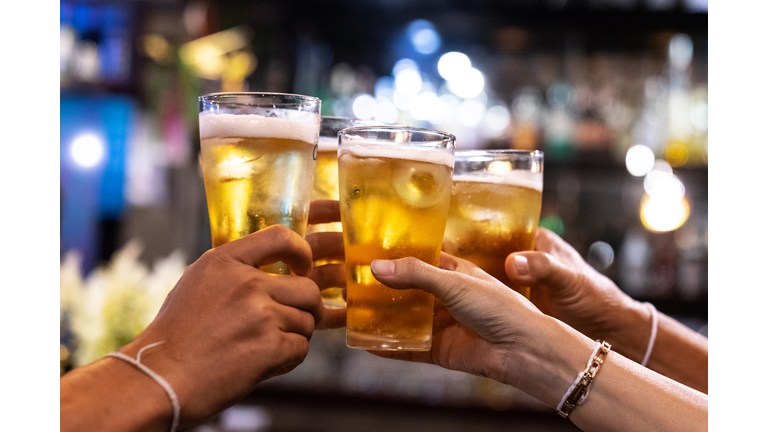 Group of happy friends drinking and toasting beer at brewery bar restaurant - Friendship concept with young people having fun together at cool vintage pub - Focus on middle pint glass - High iso image