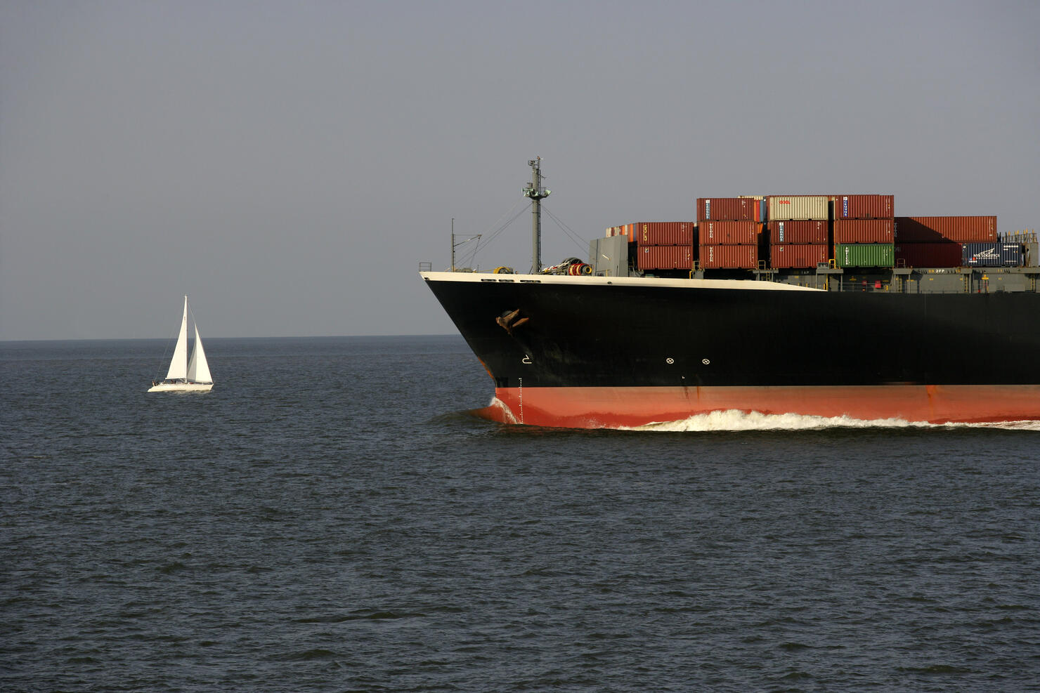 Container vessel and sailing boat at river Weser