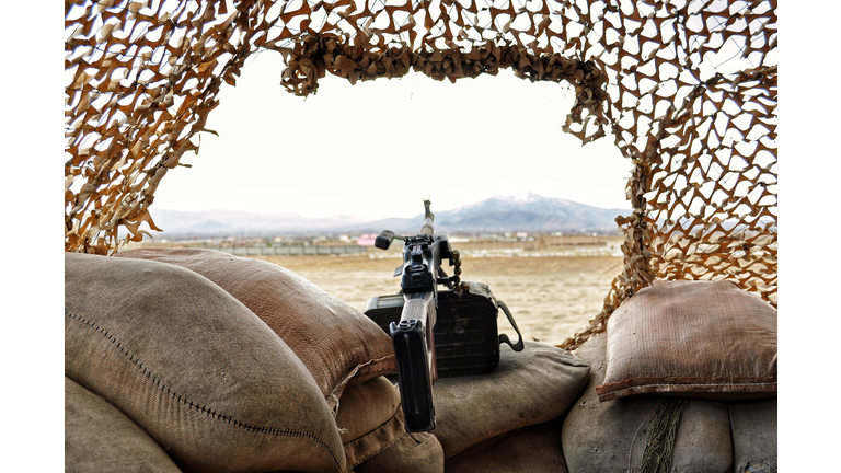 Close-Up Of Gun On Sacks Against Clear Sky