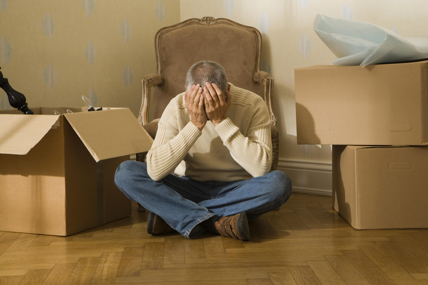 Mid adult man sitting on a hardwood floor and suffering from a headache