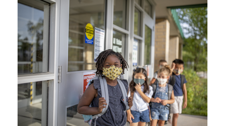 Diverse group of elementary school kids go back to school wearing masks