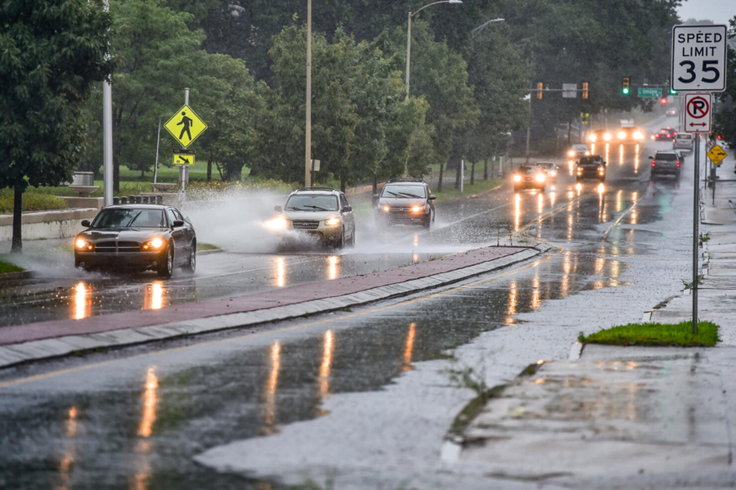 Vehicles drive through puddled waters on River street in