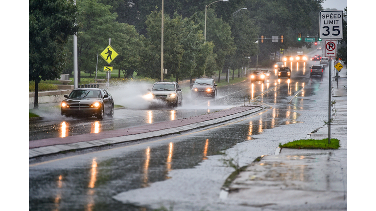 Vehicles drive through puddled waters on River street in