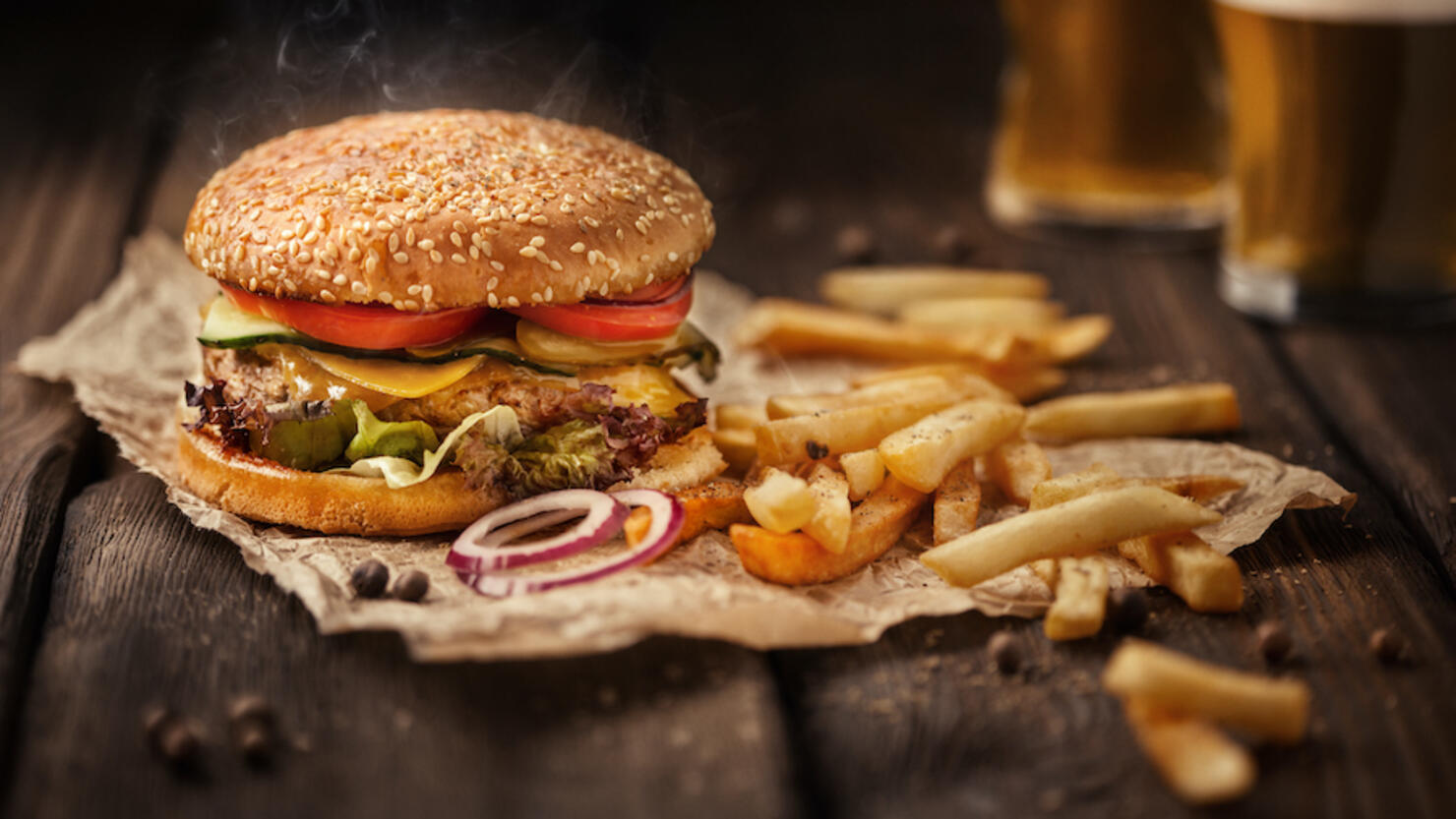 Tasty hamburger with french fries and beer on wooden table