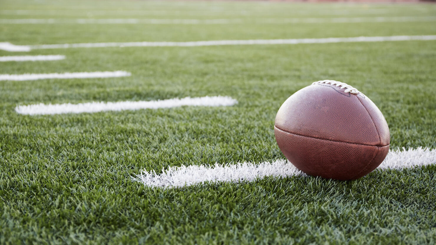 Close up of American football ball on green playing field