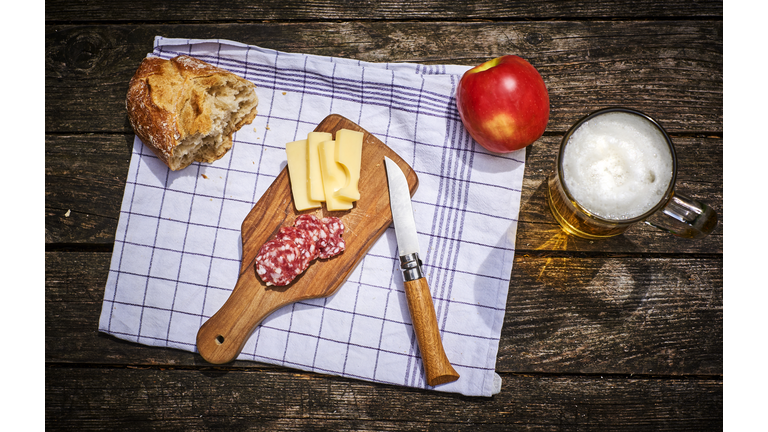 Snack with bread, cheese, salami, apple and glass of beer