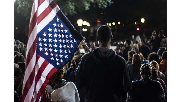 Rear View Of Man Holding American Flag In Crowd