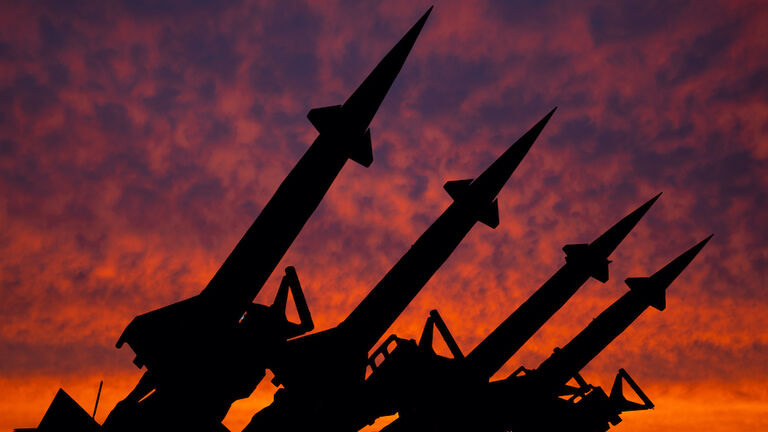 Four rockets of anti-aircraft missile system are directed upwards against the background of sunset