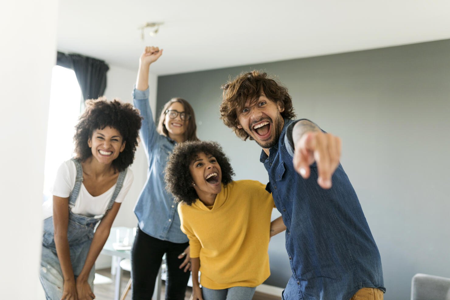 Portrait of cheerful friends at home with man pointing his finger