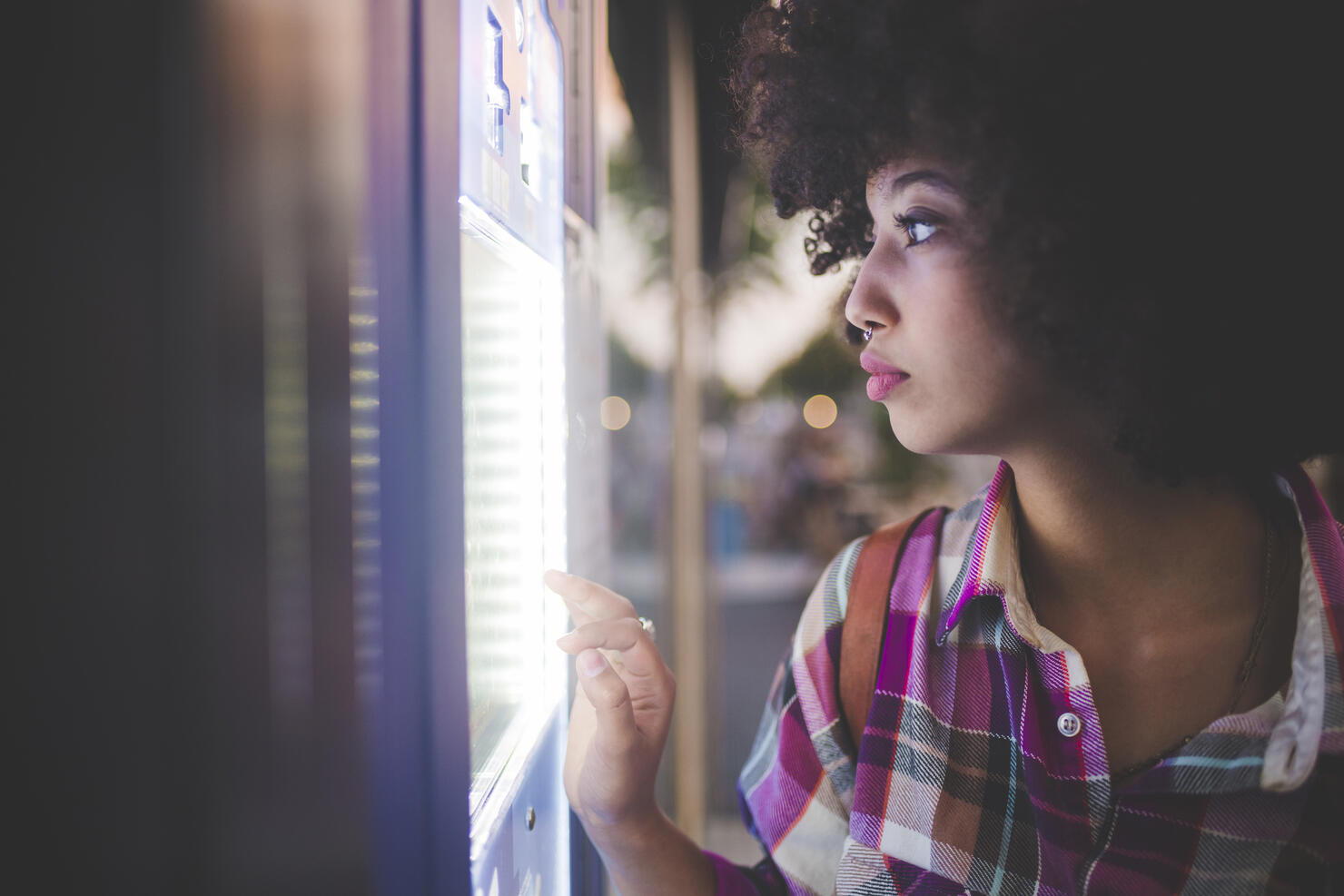 Young woman with afro hairdo using touchscreen vending machine in the city