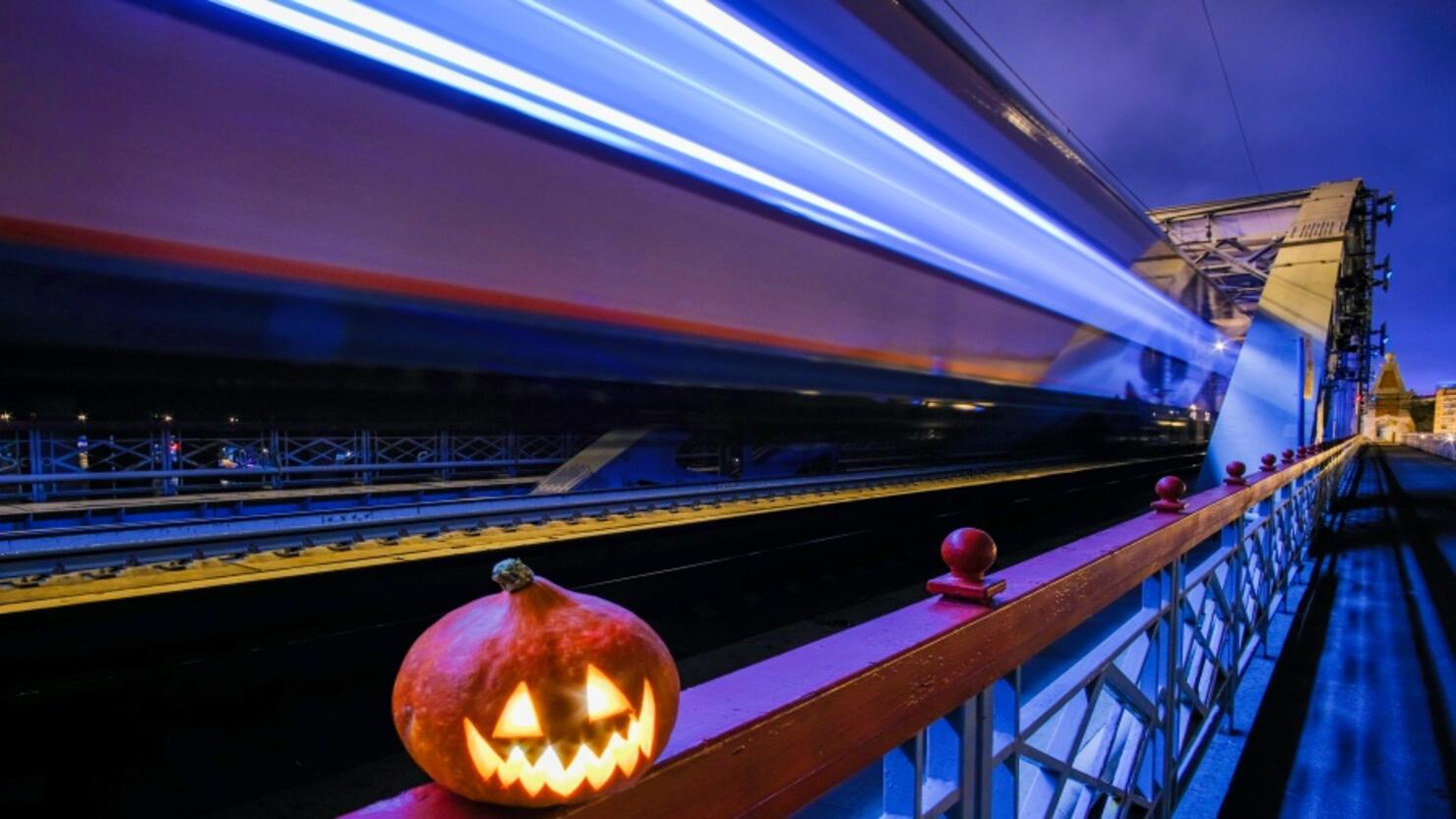 Halloween pumpkin with a glowing grimace at night on the railway bridge.