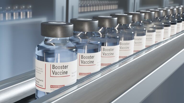 Vials of booster vaccine on conveyor in pharmaceutical factory