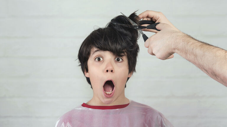 Portrait Of Shocked Boy With Mouth Open Getting Hair Cut