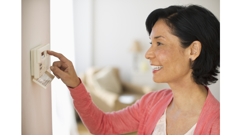 USA, New Jersey, Jersey City, Mature woman adjusting room temperature