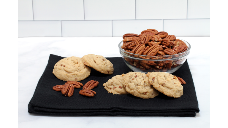 Pecan sandies cookies in front of a bowl of pecan halves.