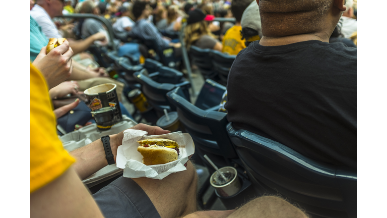 Man sitting in stadium eating hot dog