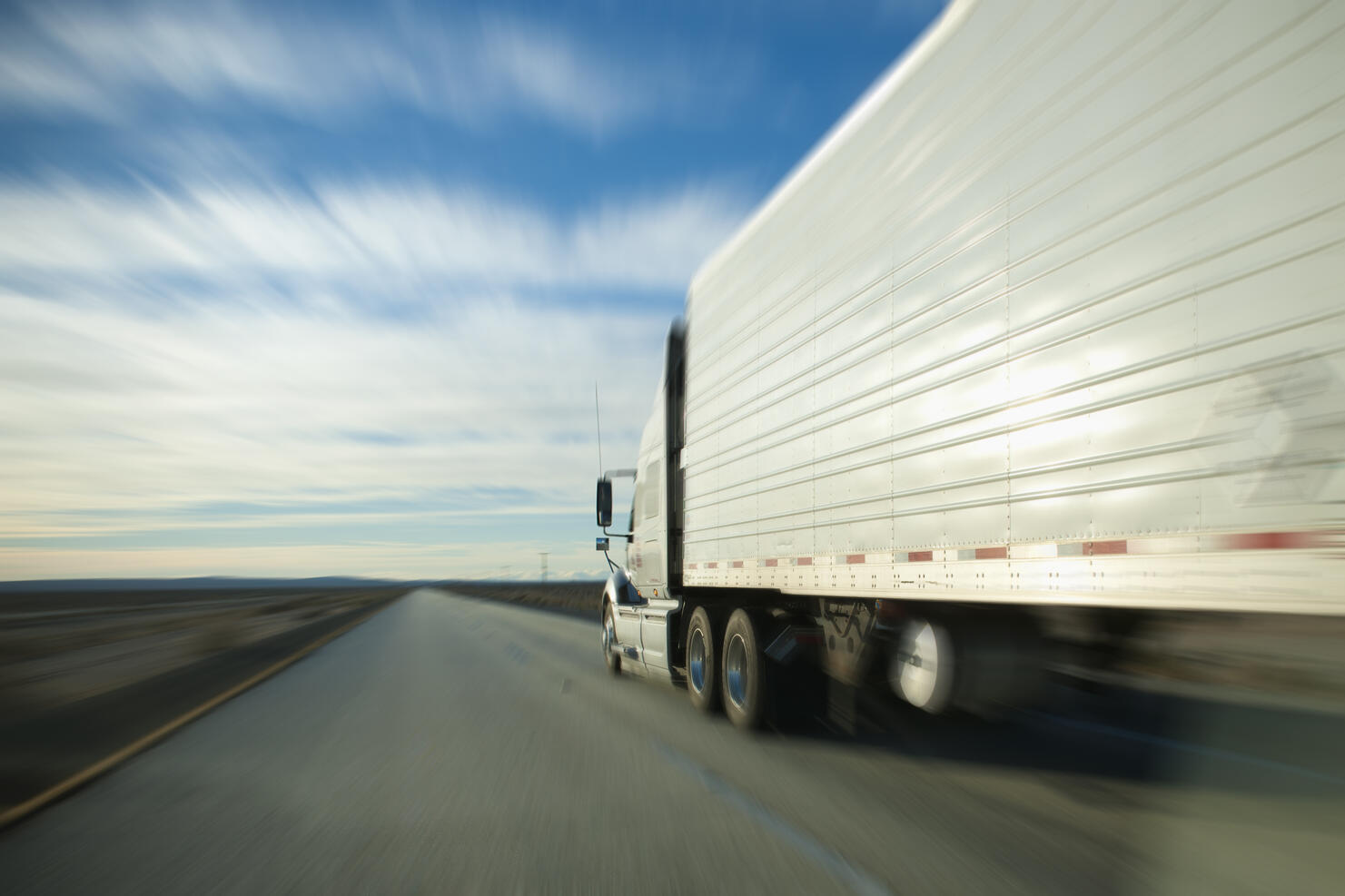 Semi truck and trailer zooming down the highway