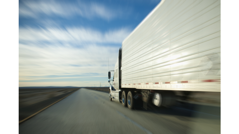 Semi truck and trailer zooming down the highway