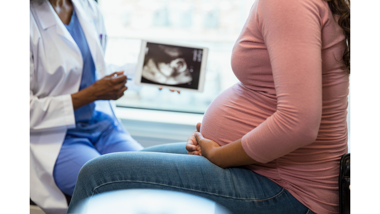 Focus on foreground as doctor shows ultrasound in background