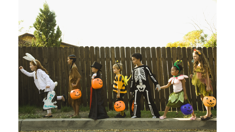 Children in Halloween costumes holding hands