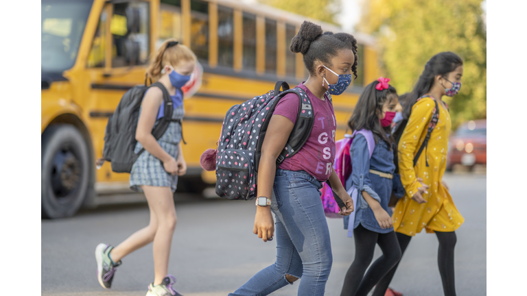 Multi-ethnic group of students crossing the road after getting off the bus