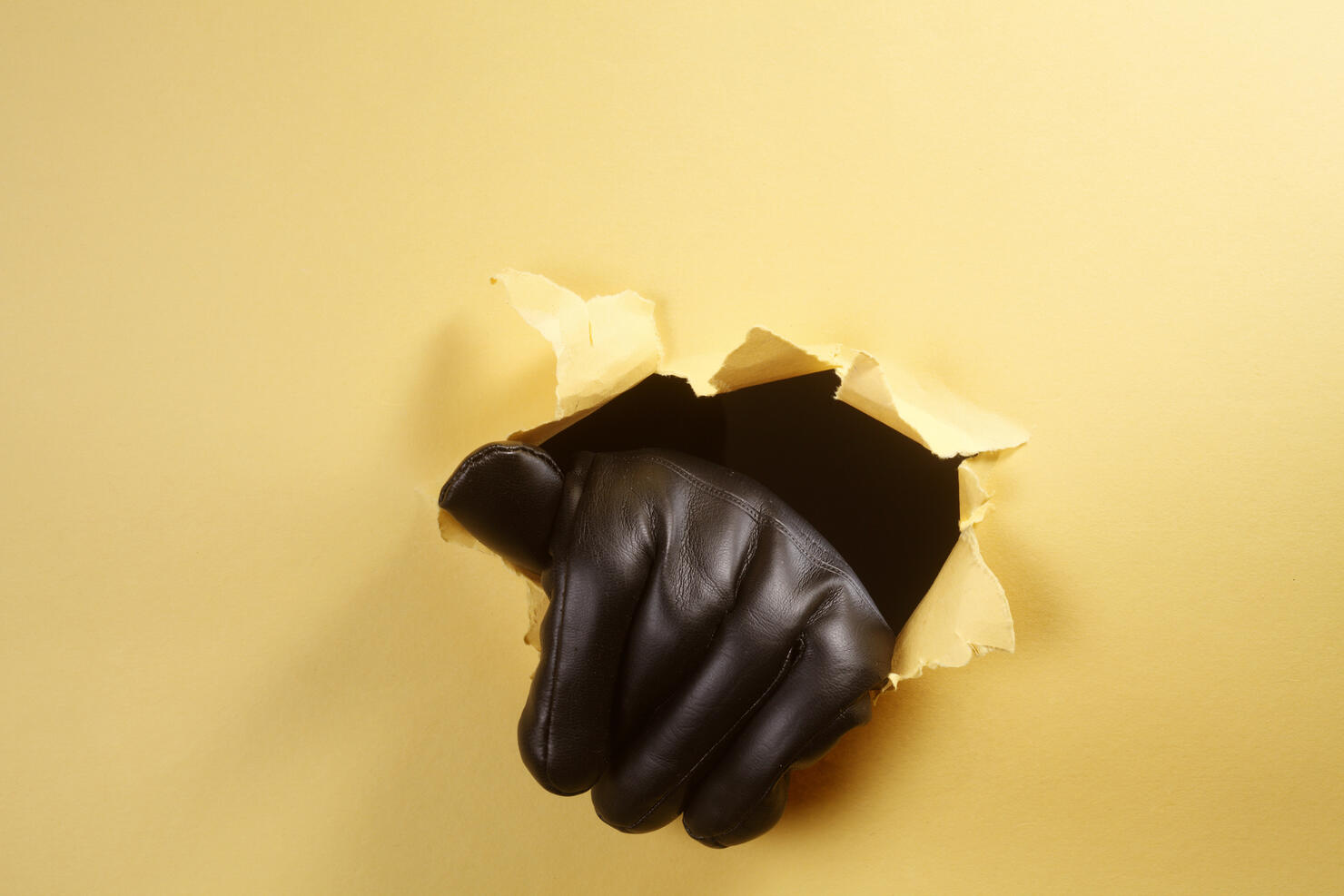 Cropped Hand Of Criminal Wearing Glove While Tearing Paper