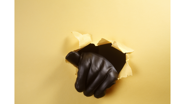 Cropped Hand Of Criminal Wearing Glove While Tearing Paper