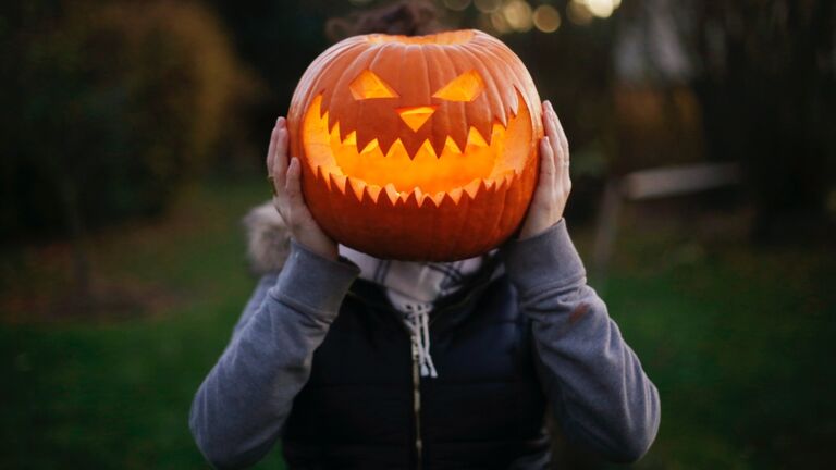 A girl with Halloween pumpkin in front of her head