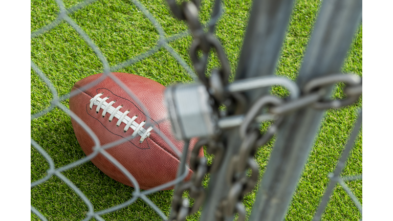 Looking through a chainlink fence gate that is locked with a padlock at American Football